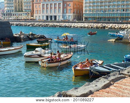 Naples Italy - August 7 2017. People enjoying the a sunbathing in fishing boats moored in Borgo Marinari harbor of Megaride island. Naples. Campania Italy.