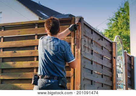 Man with artificial heart strokes a wood fence in the garden.