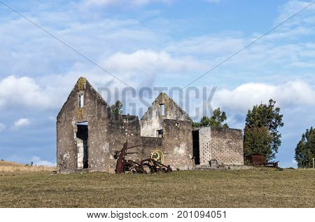 Rural old abandoned derelect farm building on dry winter landscape against blue cloudy sky