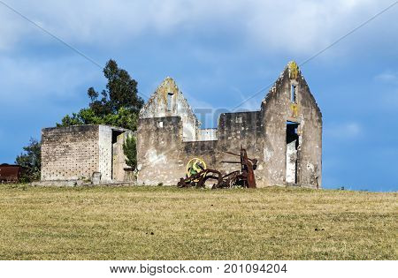Rural old abandoned derelect farm building on dry winter landscape against blue cloudy sky