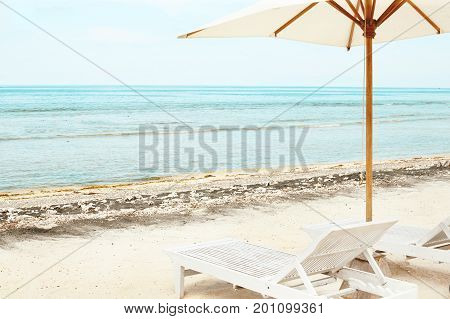 Beach Sun chairs and parasol on exotic tropical white sandy ocean beach
