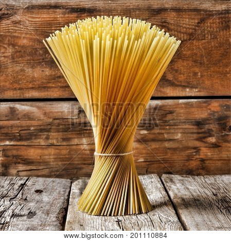 A bunch of Italian spaghetti on a wooden background. Concept: traditional Italian cuisine