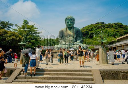 TOKYO, JAPAN JUNE 28 - 2017: Crowd of people posing and taking pictures at monumental bronze statue of the Great Buddha in Kamakura, Japan.
