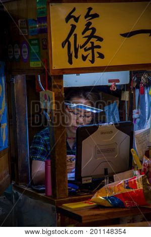 TOKYO, JAPAN JUNE 28 - 2017: Unidentified woman working in a coputer in the Fish Market Tsukiji wholesale in Tokyo Japan, Tsukiji Market is the biggest wholesale fish and seafood market in the world.