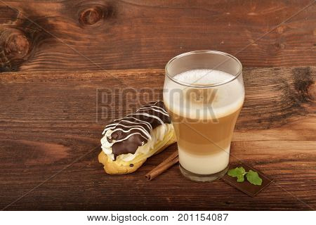 Latte macchiato and éclair. Breakfast time. Low key photo.