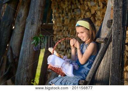 Cute smiling little girl holding a basket of flowers. Portrait in profile