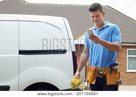 Electrician Outside House Checking Message On Mobile Phone