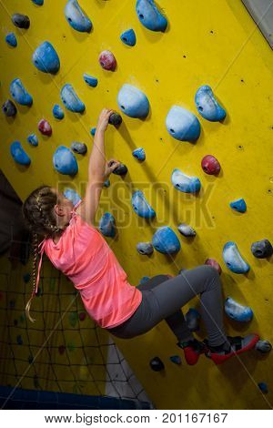 Teenage girl practicing rock climbing in fitness studio
