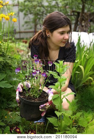 teenager girl with flowers on pot gardening in the green summer garden