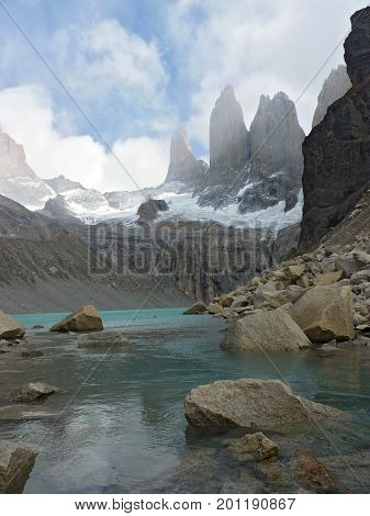 Torres del Paine partially covered by clouds and their light blue glacial lake. The picture was taken in Torres del Paine National Park Chile.