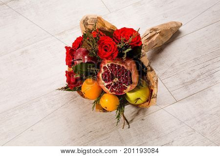 Unusual presents concept. Prettily wrapped composition of red roses and fruits.
