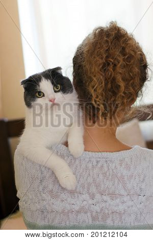Girl holding a cat on her shoulder