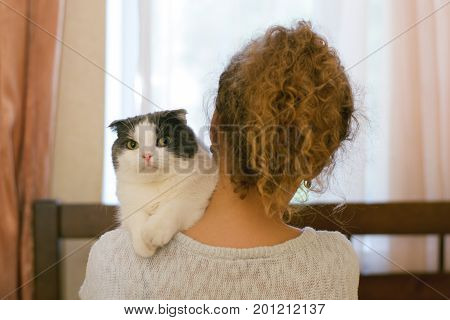 Girl holding a cat on her shoulder
