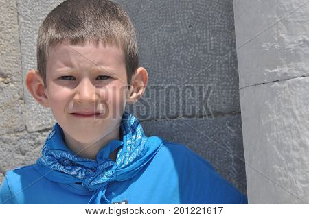 A gloomy boy with milk teeth in a shirt and a bandage laughing on a sunny day.