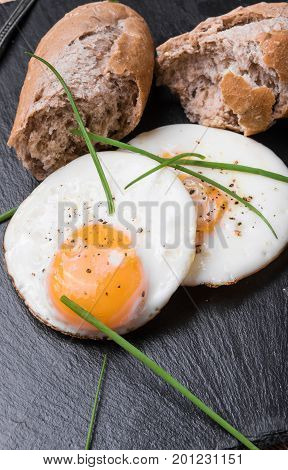 Roeasted Round Eggs with Fresh Bread on Black Stone Board with Herbs
