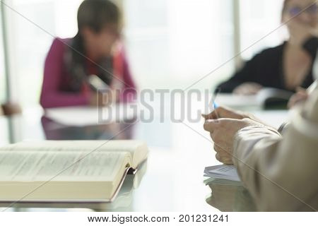 Woman in office, working with some sheets, pen and smartphone and pen in her hand. Blurred background.