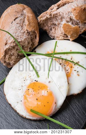 Roeasted Round Eggs with Fresh Bread on Black Stone Board with Herbs