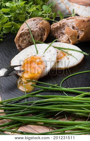 Roeasted Round Eggs with Fresh Bread on Black Stone Board with Herbs