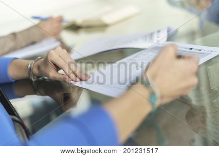 Woman in office, working with some sheets, pen and smartphone and pen in her hand. Blurred background.