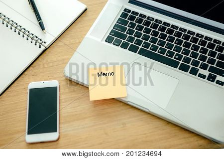 The computer laptop on the wooden table with note mobile phone and notebook.