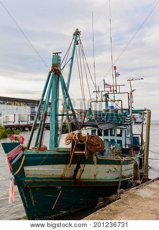 A wooden fishing boat moored to a pier in to the village in Thailnd province Khlong Yai