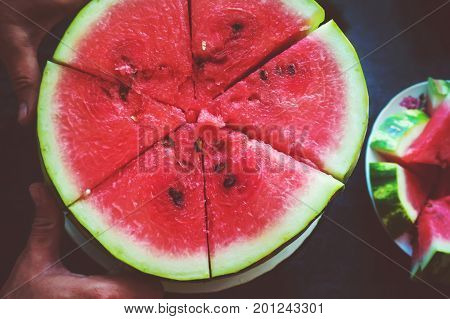 A man cuts a ripe red watermelon. Slices of watermelon closeup