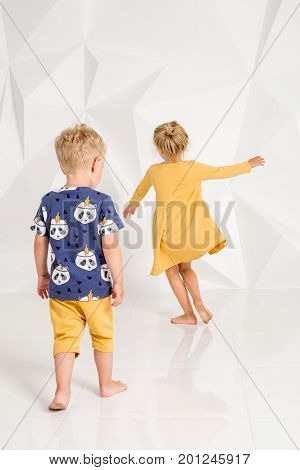 Brother and sister playing and smiling in a white studio. Little children on studio shot