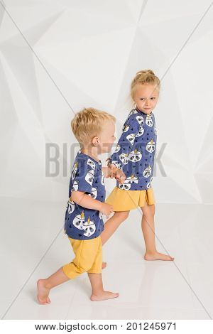 Brother and sister playing and smiling in a white studio. Little children on studio shot