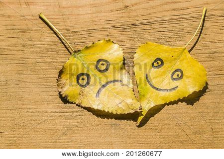 Yellow Leaves With A Picture Of Happy And Sad On An Old Wooden Background With Cracks