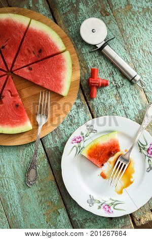 Fresh watermelon as vegan pizza with pizza knife and tire-bouchon on shabby wooden table above view