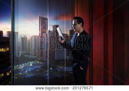 Young asian businessman holding and using digital tablet . evening scene .