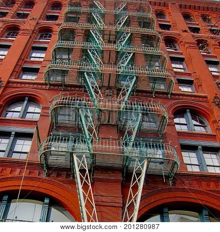 Tall red bricked building with green fire escape