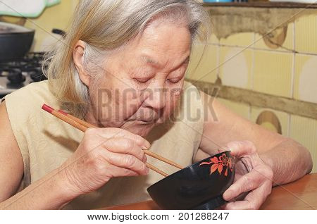 Old Woman Eating On A Bowl