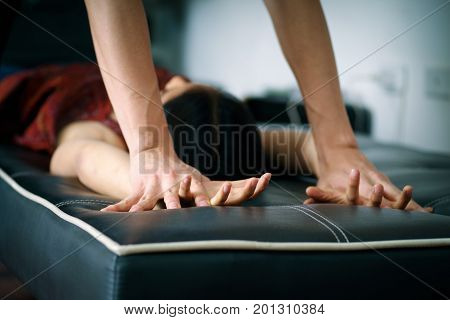 Close up man's hands holding a woman hands over a black couch for rape and sexual abuse concept.