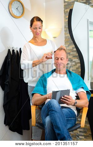 Female Hairdresser Cutting Hair Of Man
