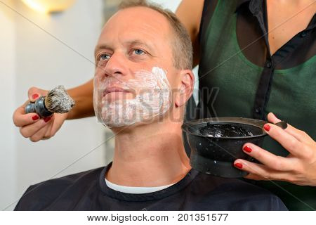 Female Hairdresser Shaving  Beard Of Man