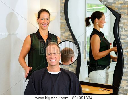 Female Hairdresser Cutting Hair Of Man