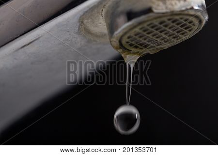 Old leaking faucet with stone and calcium sediments due to hard water.