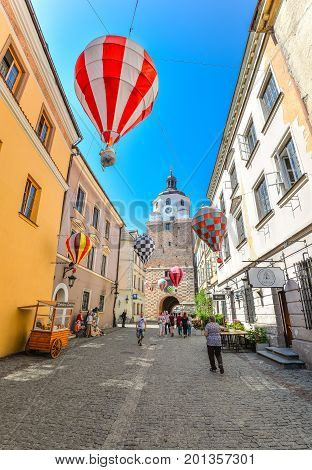 Lublin, Poland - August 10, 2017: Beautiful street and old bright buildings in the old town of Lublin, Poland. View on Cracow gate, Lublin. Mountebanks Carnaval in Lublin old town.