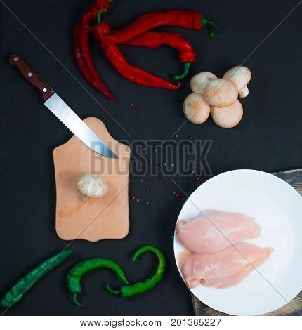 raw chicken wings with herbs in a transparent bowl Cauliflower with tomatoes and herbs and hot peppers with mushrooms on wooden background top view close up.