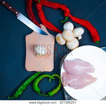 raw chicken wings with herbs in a transparent bowl Cauliflower with tomatoes and herbs and hot peppers with mushrooms on wooden background top view close up.