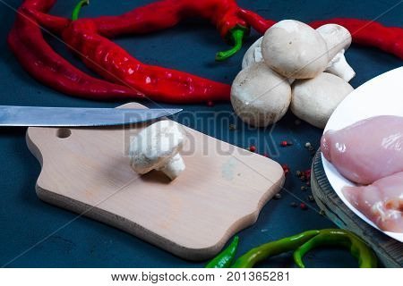 raw chicken wings with herbs in a transparent bowl Cauliflower with tomatoes and herbs and hot peppers with mushrooms on wooden background top view close up.