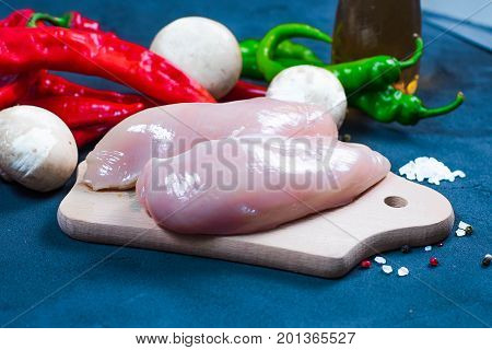 raw chicken wings with herbs in a transparent bowl Cauliflower with tomatoes and herbs and hot peppers with mushrooms on wooden background top view close up.