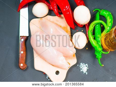 raw chicken wings with herbs in a transparent bowl Cauliflower with tomatoes and herbs and hot peppers with mushrooms on wooden background top view close up.