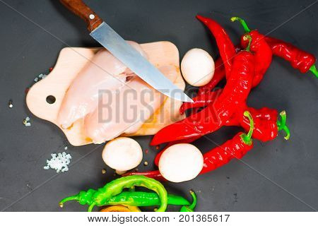 raw chicken wings with herbs in a transparent bowl Cauliflower with tomatoes and herbs and hot peppers with mushrooms on wooden background top view close up.