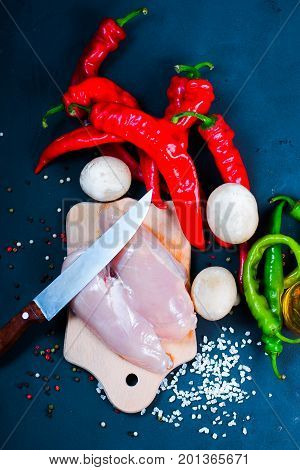 raw chicken wings with herbs in a transparent bowl Cauliflower with tomatoes and herbs and hot peppers with mushrooms on wooden background top view close up.