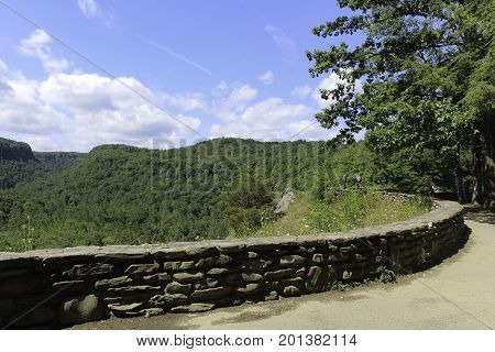 Overlook at Letchworth State Park in New York. Footpath with a stone wall. View of the forest and blue skies with white clouds