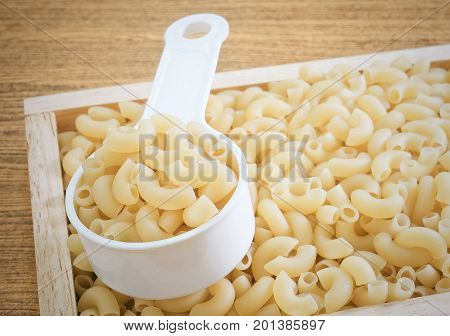 Food and Cuisine Uncooked and Dried Elbow Macaroni or Gomiti Pasta in Plastic Measuring Cup.