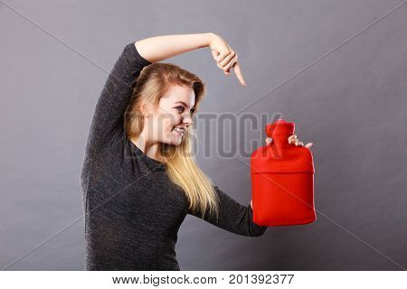 Smiling calmly woman holding warm hot water bottle feeling pleasant heat pointing at this object