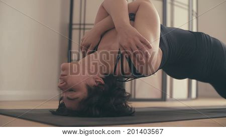 A young woman performing yoga-asanas in the hall. Setu bandhasana